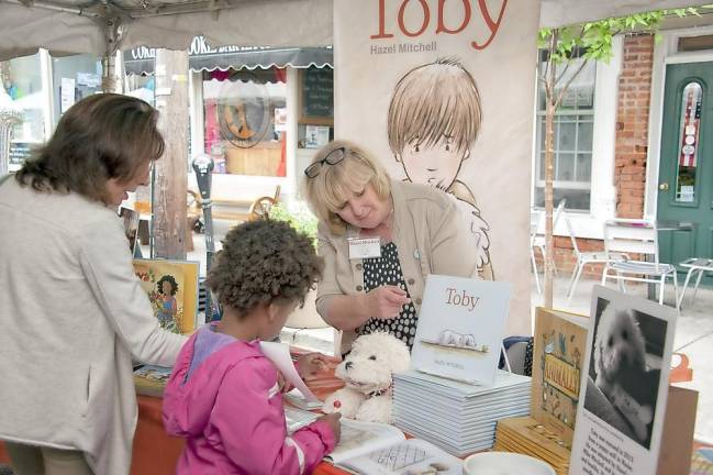 Author Hazel Mitchell discusses her book with a young reader. Photo provided by Albert Wisner Public Library.