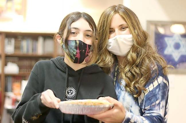 Chana Burston, who leads CTeen, is pictured with CTeen member Ari Eisner of Monroe getting ready to put the pumpkin pie into the oven that teens made to help community for Thanksgiving.