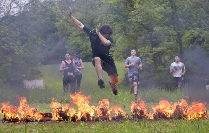Thousands participate in Warrior Dash at Warwick Day Camp Photo by Robert G. Breese Participants of the Warrior Dash jump the fire obstacle on Saturday.