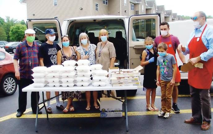 On Sunday and Monday, Sept. 6 and 7, Hugs for Courage distributed more than 400 prepackaged “Labor Day” BBQ lunches donated by Stephen Kitar, owner of Sam’s Meat Warehouse in the Village of Florida, to Warwick seniors as a symbol of gratitude for being key members of the community. Carmela Borrazas, cofounder of Hugs for Courage (third from left) and Stephen Kitar, owner of Sam’s Meat Warehouse in the Village of Florida (Far right with his family) were joined by volunteers and senior residents of Liberty Green to deliver prepackaged “Labor Day” BBQ lunches. Provided photo.