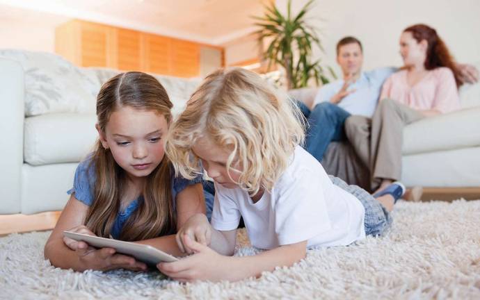 Experts say keep Amazon’s Alexa away from your kids Siblings using tablet together on the living room floor