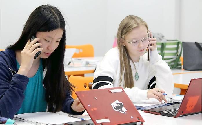 Sophia and Grace, Seward students in the DL college psychology course, use their mobile phones to interact with their peers at Averill Park High School outside of Troy.