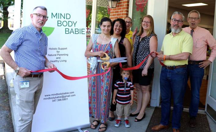 Photo by Roger Gavan On Friday, June 29, Warwick Supervisor Michael Sweeton (left), Mayor Michael Newhard (right) and members of the Warwick Valley Chamber of Commerce joined founder Anna Lopez (center) and Too Sweet Kids owner Espi Ahad (center right) to celebrate the grand opening of Mind Body Babie.