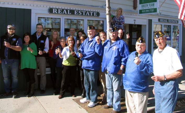 Go green in November for veterans Photo by Roger Gavan Event coordinator Jen DiCostanzo, an associate broker at the Green Team Real Estate office in the Village of Warwick, climbs a ladder to install a green spotlight outside the Green Team Real Estate office in the Village of Warwick. Posing with Principal Broker Geoff Green (center rear) and members of his sales associates and staff, are from left, bulb donors Tim and Scott Bieling, owners of Roe Brothers Lumber, and members of Post 214 American Legion, from left, Past Commander Walt Parkinson, Orange County Commander Frank Gilner, Historian Bruce Sutton and past Vice Commander Jim Culligan.