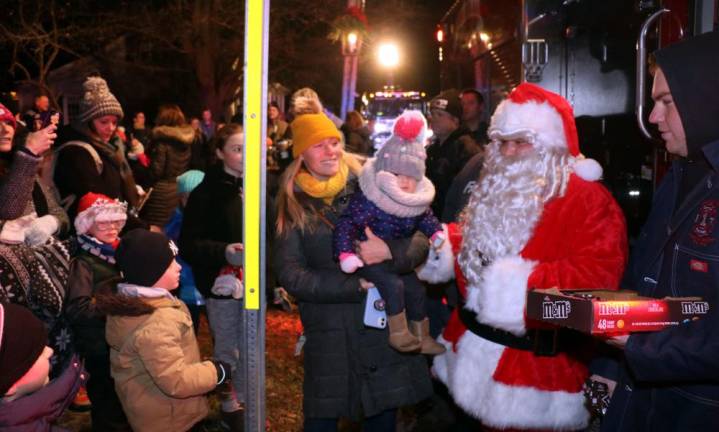 Santa, traveling in a modern fire apparatus, made his usual early surprise visit and handed out goodies to the excited children who lined up to greet him.