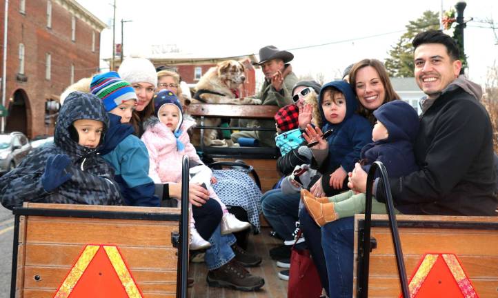 Last weekend to take advantage of free holiday Horse & Buggy rides in downtown Warwick Riders wave for the camera as they begin their tour of downtown Warwick with Sean Giery and his team of Percherons, Jack and Bob, along with their mascot “Butch,” who enjoys riding shotgun.
