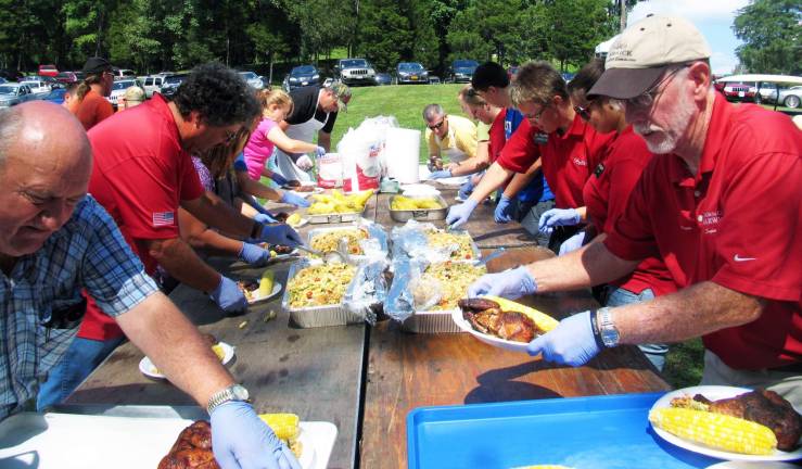 Senior barbecue draws more than 700 people Photo by Roger Gavan Town of Warwick Supervisor (right) put on his gloves to help fill the trays of chicken dinners with fresh corn on the cob.