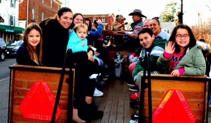 Riders, including “Lil Dale,” next to driver Sean Giery,.wave farewell as they prepare to take a free horse and buggy ride through the Village on Sunday, Dec. 5. Photo by Roger Gavan.