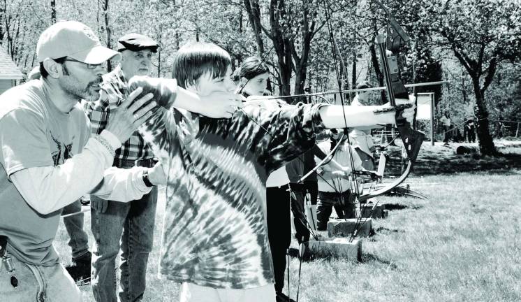 Young sports men and women Photo by Ed Bailey Henry Scarle, 12, of Greenwood Lake, gets instrution from Angel Davila on the bow and arrow range.