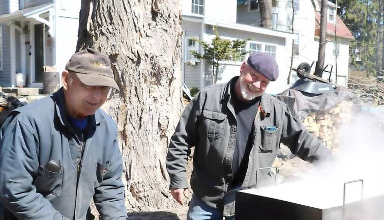 Pat Gallagher (right) appreciates a helping hand from John Worobok during the annual tapping of his maple trees and boiling down the raw sap over a wood fire.