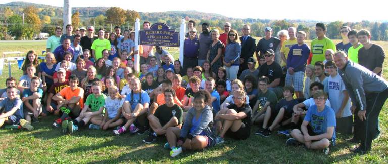 Photos by Roger Gavan On Monday, Oct. 17, Warwick Valley High School coaches, staff, friends and student athletes gathered on the picturesque cross country track at Sanfordville Elementary School to honor and celebrate the long career of XC/Track and Field Coach Richard Furst (standing just to right of sign) by unveiling a finish line sign in his name.