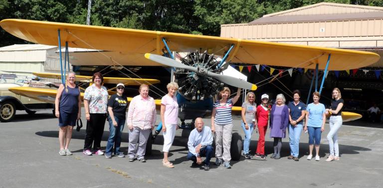 A group of members of the North New Jersey Chapter of the Ninety-Nines, an International organization of women pilots, pose by a PT 17, a World War II U.S. Army primary pilot trainer, with Warwick Municipal Airport Manager Dave Mac Millan.