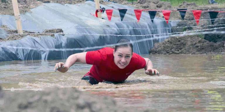 Thousands participate in Warrior Dash at Warwick Day Camp Photo by Robert G. Breese A woman makes her way through the muddy water and under barbed wire during the Warrior Dash in Warwick on Saturday.