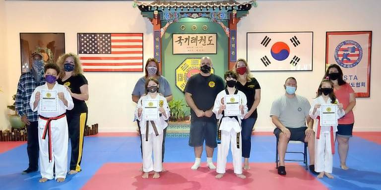 From left to right, Chosun students Maximus Sherman, Kylie Frey, Lucas Greh and Gianna Ricco, along with their parents, accepting their Chosun Junior Assistant Instructor credentials. Provided photos.