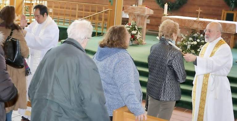 Parishioners receive the blessing of throats administered by Parochial Vicar Father Reynor Santiago (left) and Rev. Jack Arlotta, pastor of the Church of St. Stephen, the First Martyr: The blessing reads: Through the intercession of Saint Blase, bishop and martyr, may God deliver you from every disease of the throat and from every other illness: In the name of the Father and of the Son and of the Holy Spirit.