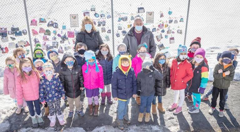 Kindergarten students from Theresa Canfield's class hang up cold weather items donated by all of the classes at Pine Island Elementary School on a fence at Pine Island Park on Feb. 26.