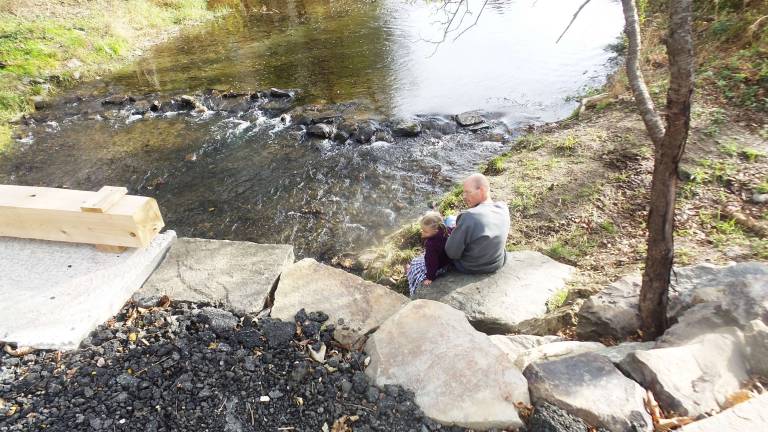 Rotten, broken, dangerous Goosepond bridge is repaired Ann and her father, Arno Wright, from the Bruderhof Bellevale Community, sitting on a huge boulder enjoying the reconstructed bridge (Photo by Frances Ruth Harris)
