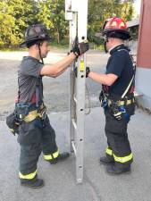 Firefighter Kevin Colomba and Lt. Kevin Hughes work to raise a 24-foot extension ladder during a drill at the at Warwick Station. Photos provided by Michael Contaxis.