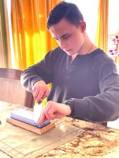 Wyatt Dul sharpers a knife with a whetstone, a skill he learned at the Repair Café.