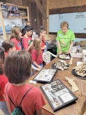 Dot Zwerin, a member of the Warwick Historical Society’s Shingle Dig Team, explains to students about some of the artifacts they unearthed at the Shingle Complex.