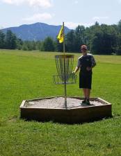 Zach Dolyle stands next to the basket on the 1,200-foot Par 5 Hole #7 at Fox Run during a practice round