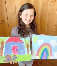 First grader Stella Kambach with her paintings of a pink flamingo and a rainbow with star-shaped clouds. Photo by Tom Bushey/Warwick School District