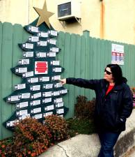 Merchant Guild President Corrine Iurato explains that donors to the Angel Tree, located on Main Street between Akin’s Drug Store and Newhard’s The Home Source, simply select the organization they would like to support and forward their donation in any amount they choose. Photo by Roger Gavan.