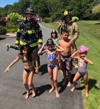 Firefighters Austin Courtney and Michael Velez-Cosgrove get help from some friends at a fire call on Saturday on Wilhelm Drive. Thanks for the pizza, kids.