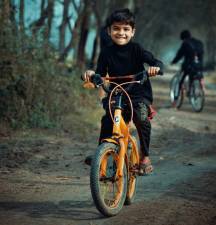 A boy happily rides his bike on an established trail.