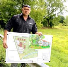 Developer Stephen Kitar poses with his plan and an artist rendition of the proposed inn outside the almost 10 acre property along West Street identified by the prominent formation known as “Pulpit Rock.”