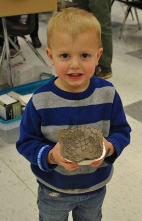A proud young potter shows off his clay project.