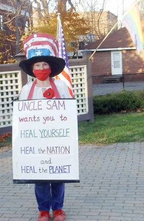 In an event sponsored by Indivisible Hudson Valley, a group of Warwick residents met on Railroad Green Sunday afternoon to celebrate the results of the election and demonstrate their commitment to healing democracy. Passersby joined in singing “America the Beautiful “and other songs of unity. With her oversized Uncle Sam hat and sign with a message of healing, Patricia DeBruhl provided a focal point for conversations with both Biden and Trump supporters. Photo provided by Alice McMechen.