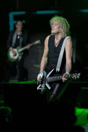 Def Leppard co-founder and bassist Rick Savage plays dyring the band's set at Bethel Woods Center for the Arts on Saturday. In the background is guitarist Vivian Campbell. Photo by Kevin Ferguson provided courtesy of Bethel Woods.