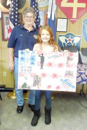 Vittoria Damiani was the fourth grade winner of the ”What Veterans Day Means To Me contest sponsored by the Florida American Legion Auxiliary Unit 1250. She used hand prints in red and blue to design banners with stars; each of the photos included in her art work were family members who have served or are serving, including her great-grandfather.