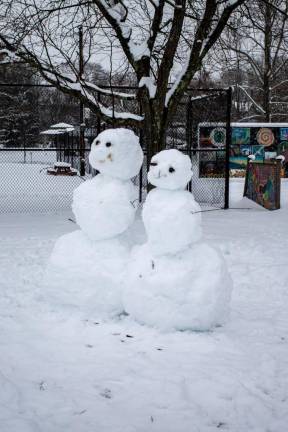A pair of snowmen watch families sledding in Stanley Deming Park after last weekend’s snow storm on Sunday, January 7.