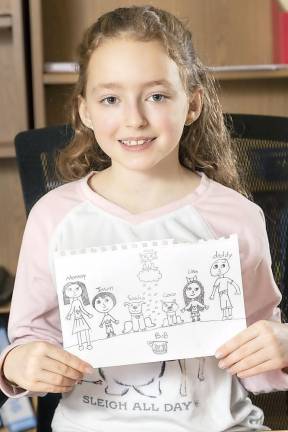 Sanfordville Elementary School third grader Lina Lauristen displays her drawing of her family, including Max the cat (sitting on a cloud above the family), her dogs Sasha and Coco and Bob the fish in a tank.
