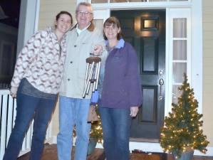 Dan and Ann Ferris and their daughter Diana Dimon (left) couldn’t find a bell in their house, so they rang some wind chimes while they stayed sheltered from the wind and rain on their porch. Photo by Joe Ebler.