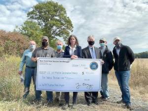 Pictured from left to right are: Left to right, Orange County Soil and Water Conservation District Chairman John Wright, SWCD Director and County Legislator Paul Ruszkiewicz, SWCD Manager Kevin Sumner, state Sen. Jen Metzger, Deputy County Executive Harry Porr, Orange County Farm Bureau President John Lupinski and Warwick Town Supervisor Michael Sweeton hold a giant check for the $400,000 grant secured by Metzger for the Wallkill Floodplain Bench Project. Provided photo.
