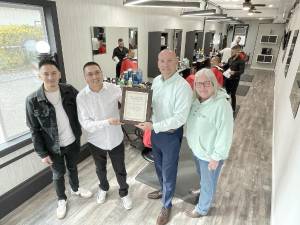 barber Erick , shop owner Iderson Suarez, Mayor Jesse Dwyer and Trustee Nancy Clifford