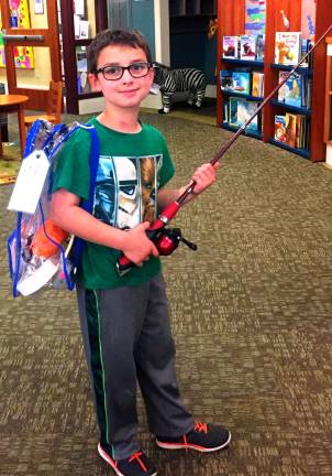 Keene Eicher is seen here modelling the fishing backpack from the Discovery Backpack collection in the Children's Department at Albert Wisner Public Library.