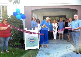 L-R: Warwick Valley Chamber of Commerce Executive Director Stefanie Keegan and Warwick Town Supervisor Michael Sweeton hold each end of the ribbon as friends and family watch Lisa Miccio make the formal cut.