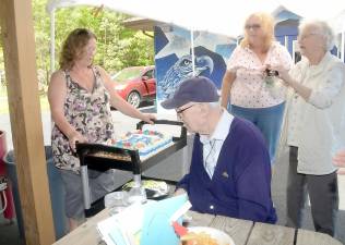 Donna Garley, the director of the Greenwood Lake Senior Center, prepares to cut the cake for Angelo Defazio on his 99th birthday. Photo by Ed Bailey