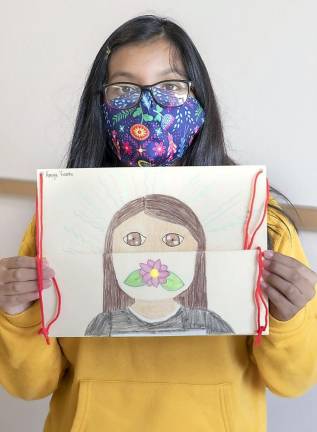Sixth grader Kenya Vicente holds up a masked self portrait she did as part of a class project.