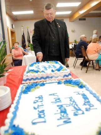 The Rev. Robert Sweeney cuts one of the three cakes at his retirement party on July 28.