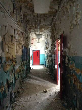 A hallway of ruins, almost artistic in its starkness, ends at a red door that leads to nowhere on the first floor of the main building of Camp LaGuardia in this 2013 photograph. Courtesy of Robert Yasinsac and his website, Hudson Valley Ruins.