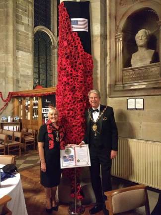 Provided photos Warwick UK Mayor Stephen Cross and his wife, Christine, pose in front of the 664 hand-crafted poppies that were shipped from Warwick, N.Y., to be displayed with thousands of handmade poppies at St Mary's Collegiate Church in England.