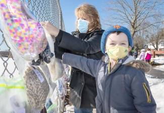Kindergarten teacher Theresa Canfield helps Kieran McCosker hang up cold weather items donated by all of the classes at Pine Island Elementary School on a fence at Pine Island Park on Feb. 26. Photos by Tom Bushey/Warwick Valley School District.