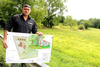 Developer Stephen Kitar poses with his plan and an artist rendition of the proposed inn outside the almost 10 acre property along West Street identified by the prominent formation known as “Pulpit Rock.” File photo by Roger Gavan.