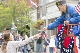 A veteran offers a small American flag to this young woman along the parade route on Main Street in the Village of Warwick this past Memorial Day, May 31. “As this Memorial Day weekend marks our first tentative steps toward reopening our lives and rejoining the world we knew, let us take meaningful actions to advance the public good,” Warwick Town Justice Peter Barlet would remark later during the ceremony. “Let us make this a year in which we reawaken a national spirit worthy of those who have given their lives to allow us that chance.” Additional photos from Memorial Day observances appear on pages 10, 11 and 13. This photo is by Robert G. Breese.