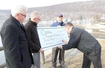 Orange County Executive Steven M. Neuhaus signs the ceremonial $20,000 check awarded to Greenwood Lake Commission as Orange County Legislator Barry Cheney, Town of Warwick Supervisor Michael Sweeton and Warwick Town Councilman Floyd DeAngelo, who also is the New York chairperson of the Greenwood Lake Commission, look on at Thomas P. Morahan Waterfront Park in Greenwood Lake on Jan. 23.